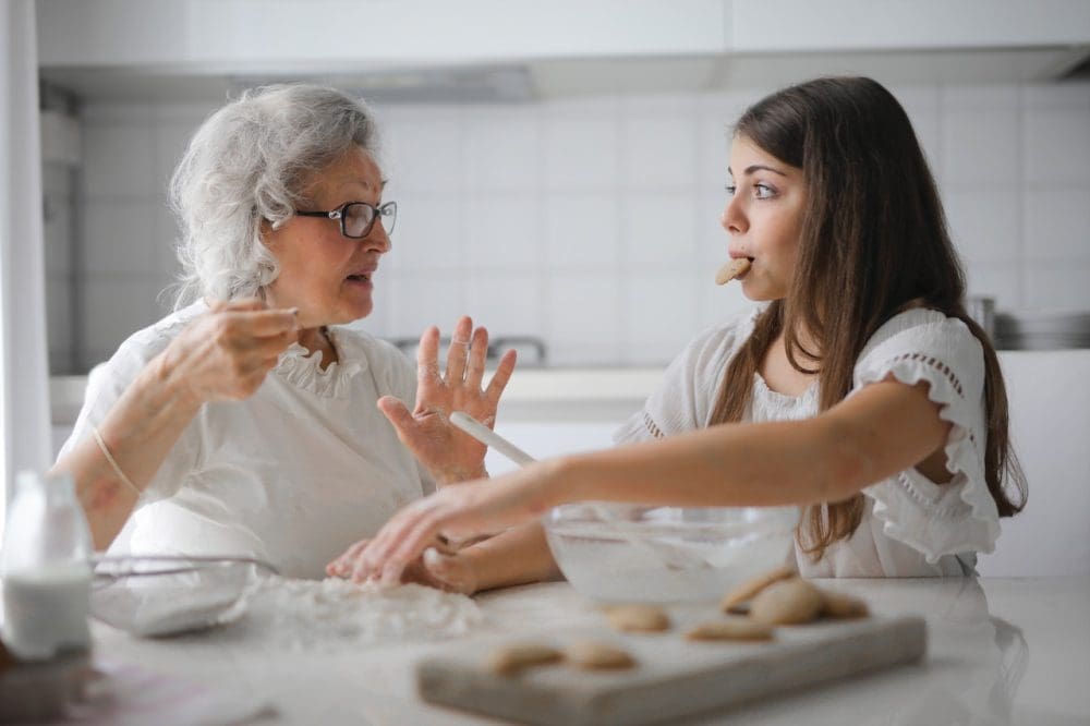 pexels-andrea-piacquadio-3768146 A happy grandmother and her young granddaughter baking delicious homemade cookies together in a bright kitchen, covered in flour and sharing a sweet moment.